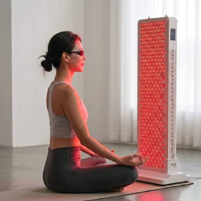 Woman using the Lumina 300 red light therapy panel at home